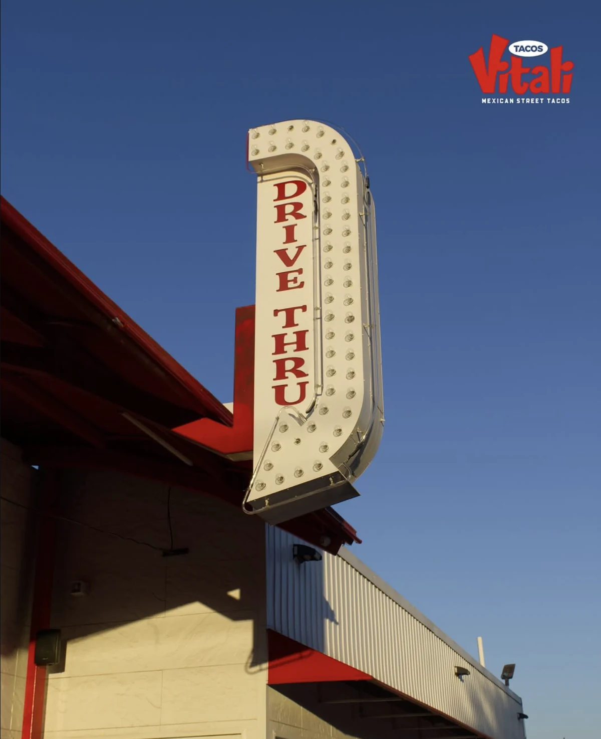 The illuminated drive-thru sign and red awnings at Vitali