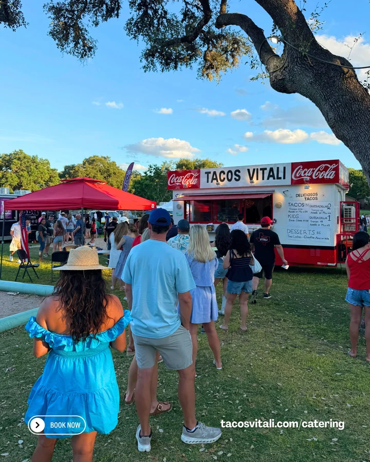 Guests line up at the Tacos Vitali food truck at an outdoor event.